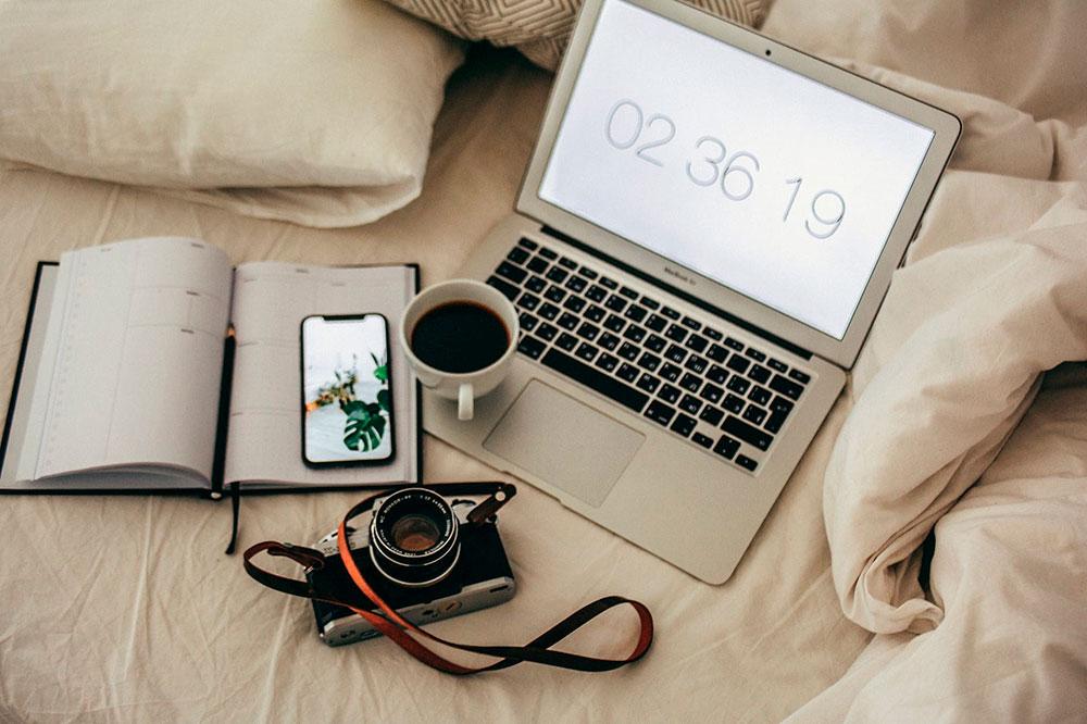 iphone y macbook en la cama con café